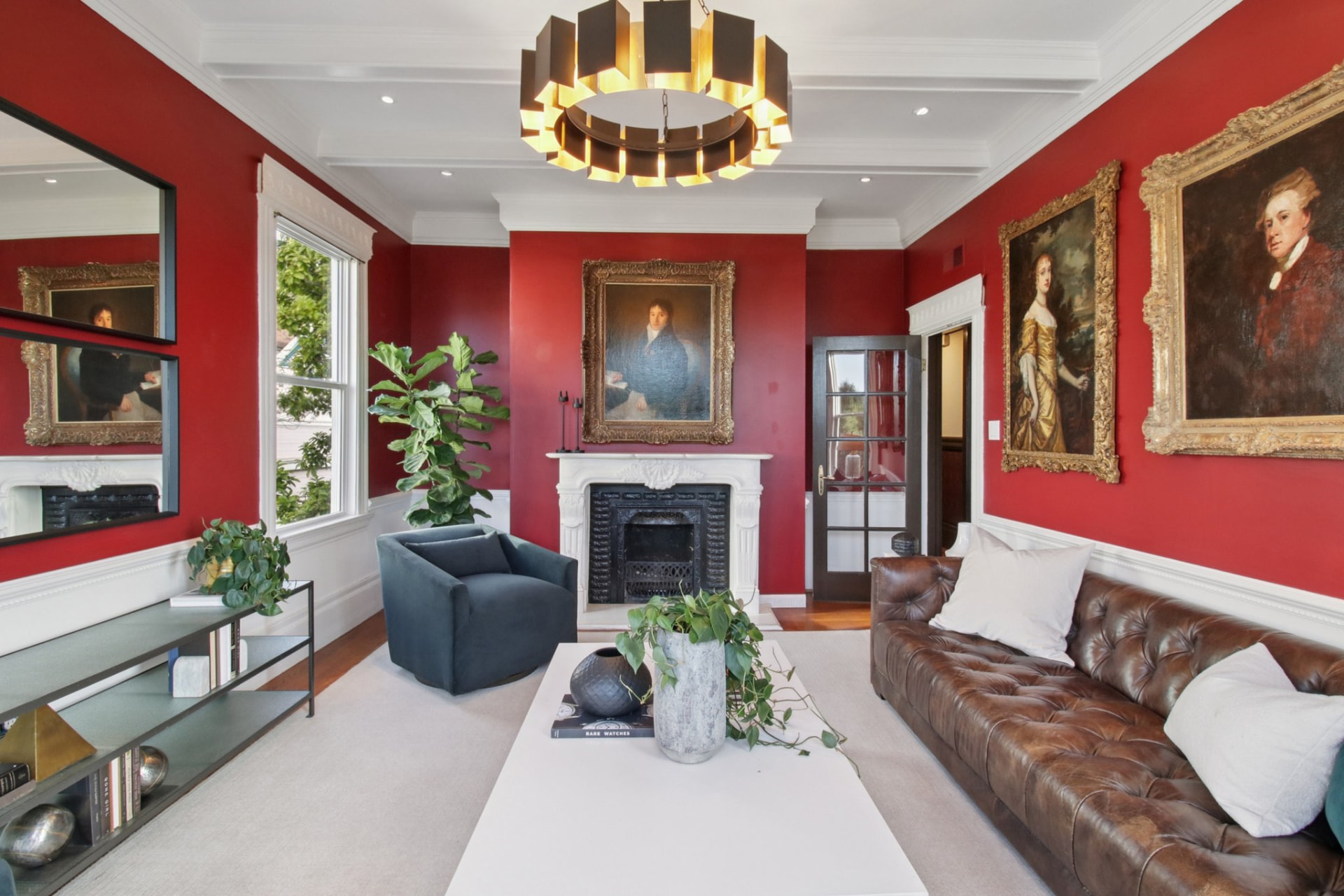 Elegant red living room with period portraits and brass chandelier